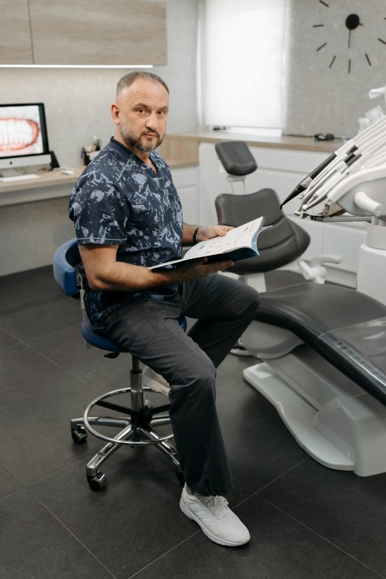 Dentist seated in modern clinic reviewing patient records inside dental office.